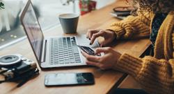 woman sitting at a laptop holding a credit card, online shopping