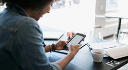 woman in a coffee shop smiling as she looks at her phone