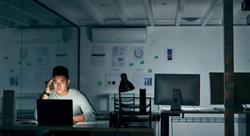 man sitting in a dark office space using a laptop