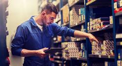 auto mechanic looks at auto parts organized on a shelf