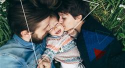 young parents kissing the cheeks of their laughing toddler