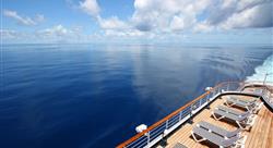 view of the ocean and a cruise ship sundeck filled with striped lounge chairs