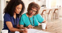 Female healthcare worker filling in a form with a senior woman during a home health visit