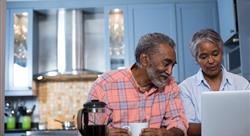 Senior couple drinking coffee and looking at laptop