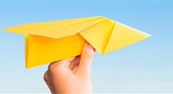 a hand holding a bright yellow paper airplane